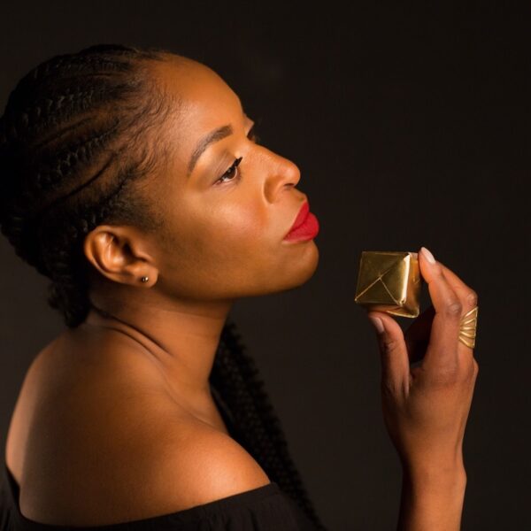 Joy Ike holding tiny gift box on black background