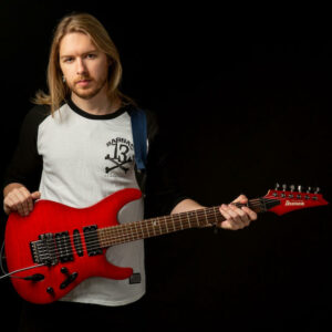 British guitarist composer Timothy Reid holding red electric guitar
