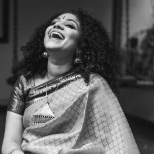 Carnatic singer Roopa Mahadevan smiling and laughing with head tilted back