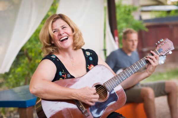 Tanya Winch playing acoustic guitar smiling