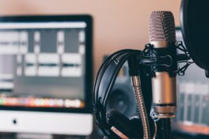 Home studio podcasting setup - a Røde NT1A microphone, AKG K171 headphones, desk stand with pop shield and my iMac running Reaper.