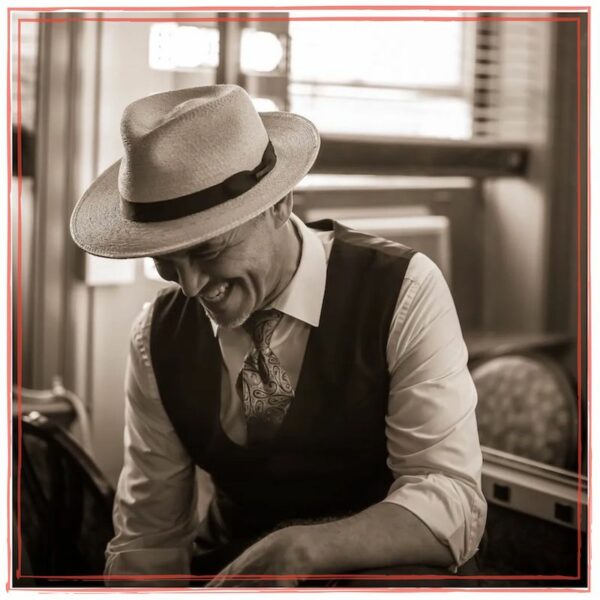 Dean Johanesen, smiling in hat, tie and vest, sepia photo | Dean Johanesen – Album Artwork Development, Song Reference Files, Journals, Record Release Mode, Balancing Creative Time, The Arc Of A Thematic Album, Writing Press Releases, Release Campaign Framework, Heightened Creativity At The Dripping Springs Songwriters Festival