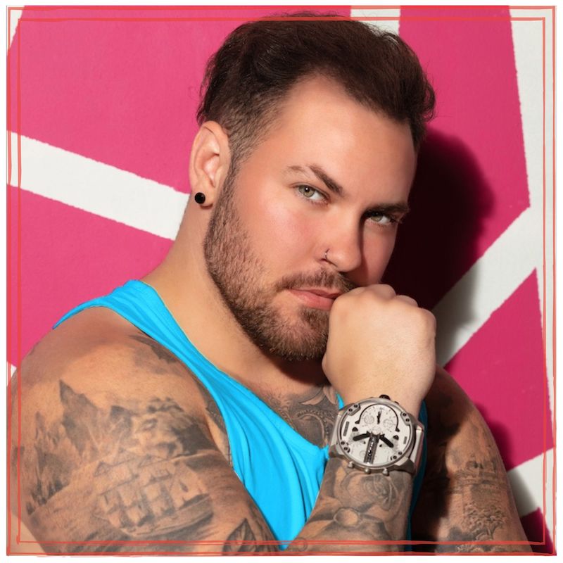 Carter Ray on pink and white background, wearing a blue tank-top and watch, fist resting on chin.