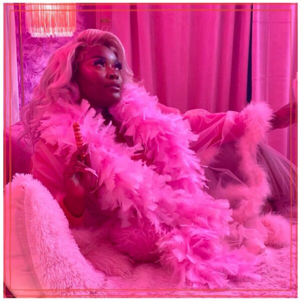 Wowashwow wearing a boa on a fainting sofa in an all deep pink setting