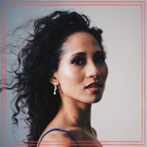 Kayana - Singer songwriter multi-instrumentalist, headshot on gray background