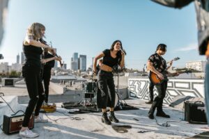 Band performing on outdoor rooftop under blue skys