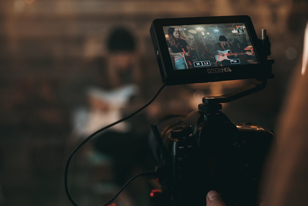 Two musicians with video camera recording a session with guitar | Photo by Kyle Loftus: https://www.pexels.com/photo/unknown-person-playing-guitar-2510428/ | Music Media Coverage