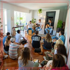 Group of people sitting in small room listening to musicians with guitars | Photo by Nano Erdozain: https://www.pexels.com/photo/group-of-people-sitting-in-small-room-listening-to-two-musicians-with-guitars-26835482/