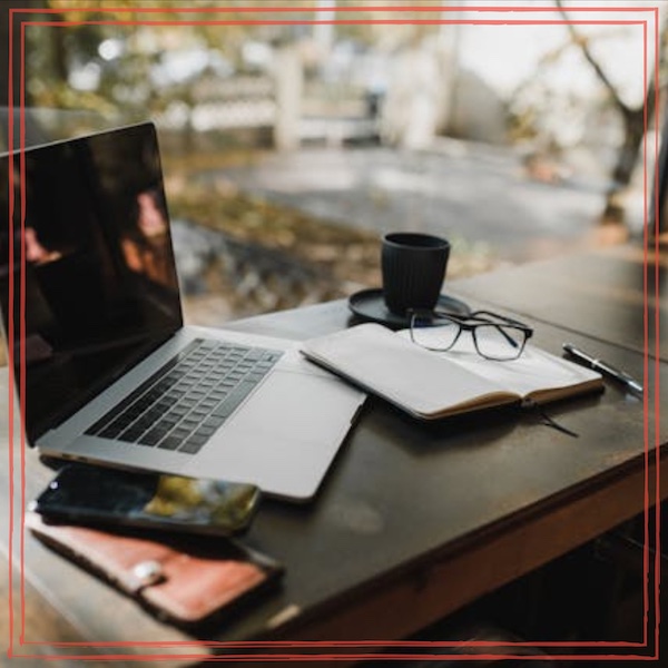 Silver laptop, notebook, and coffee cup on brown wooden table | Episode artwork Unstarving Musician